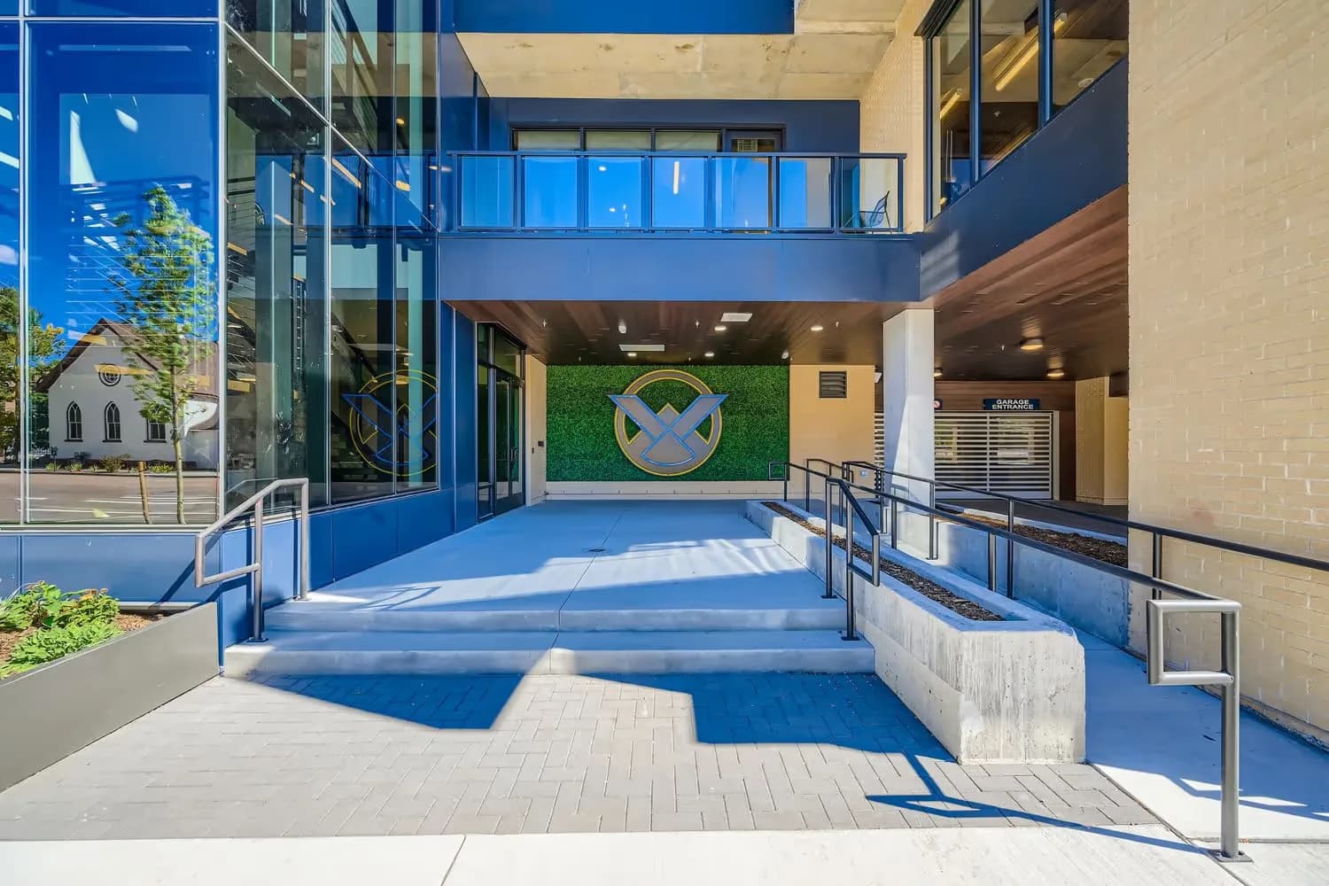 Modern apartment building entrance with the Avian logo against a green wall in Colorado Springs.