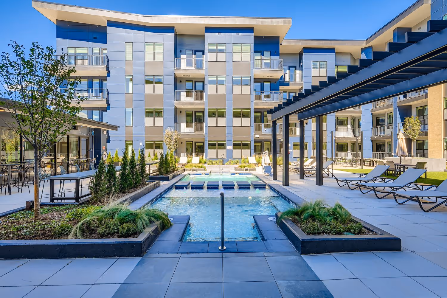 Modern courtyard pool and hot tub amenity with built-in planters and lounge chairs, surrounded by the apartment buildings at Avian in Colorado Springs, CO.