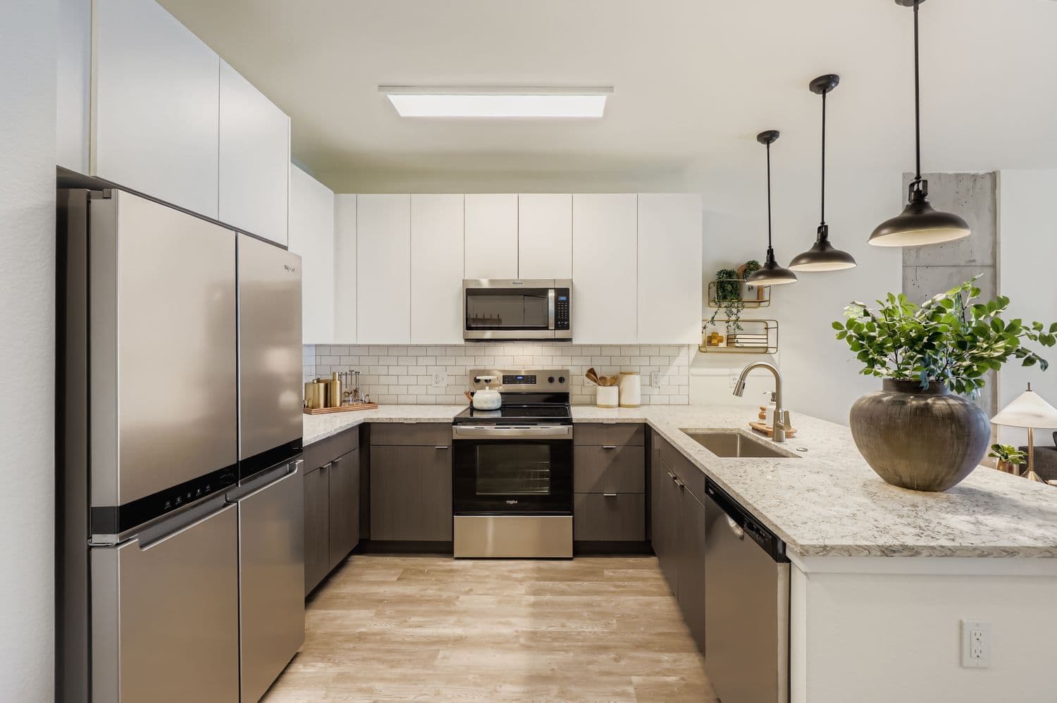 Gourmet apartment kitchen with two-tone cabinetry, white countertops, a subway tile backsplash, and a sink on the large island at Avian Apartments in Colorado Springs, CO.