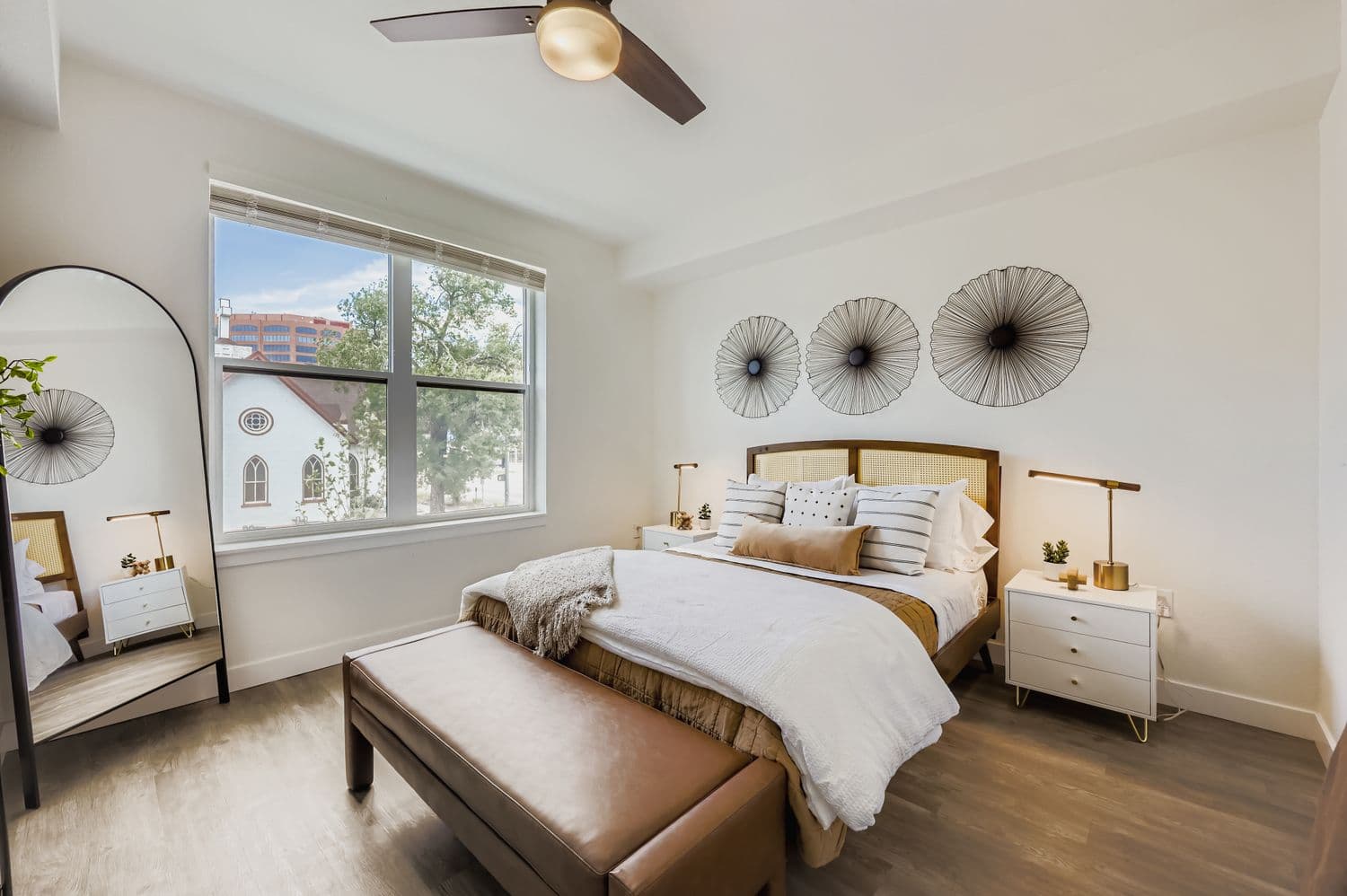 Stylish bedroom with a woven headboard, large window, and modern nightstands at Avian Apartments in Colorado Springs, CO.
