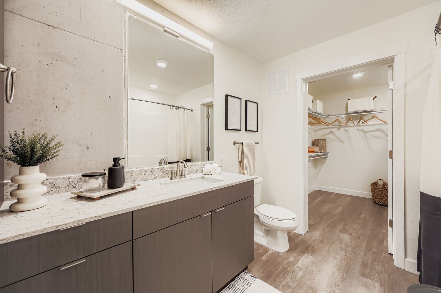 Stylish bathroom with a spacious vanity, large mirror, and open access to a large walk-in closet in an apartment at Avian Apartments in Colorado Springs, CO.