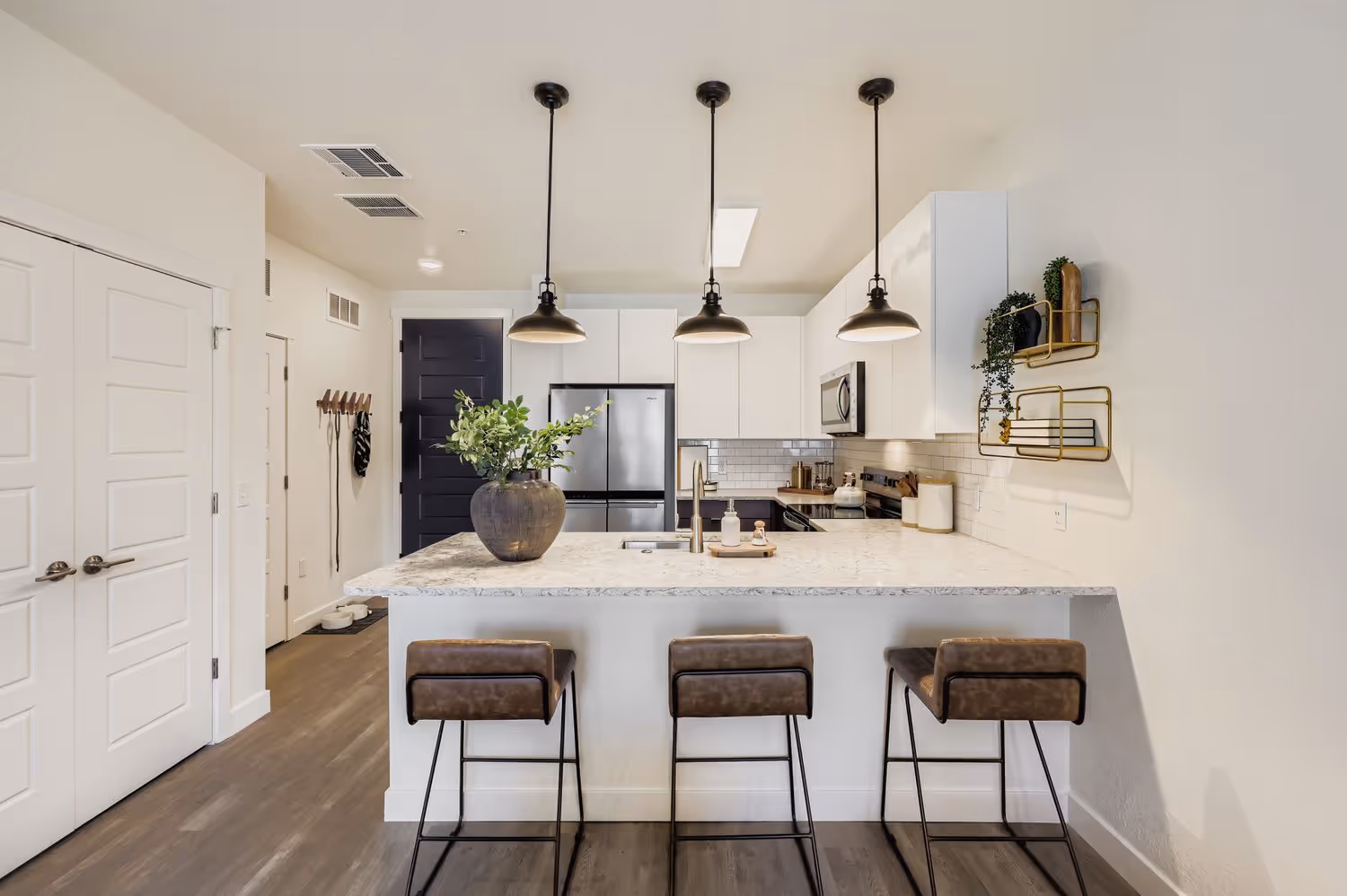 Gourmet apartment kitchen with an island, stone countertops, and modern pendant lighting at Avian Apartments in Colorado Springs, CO.