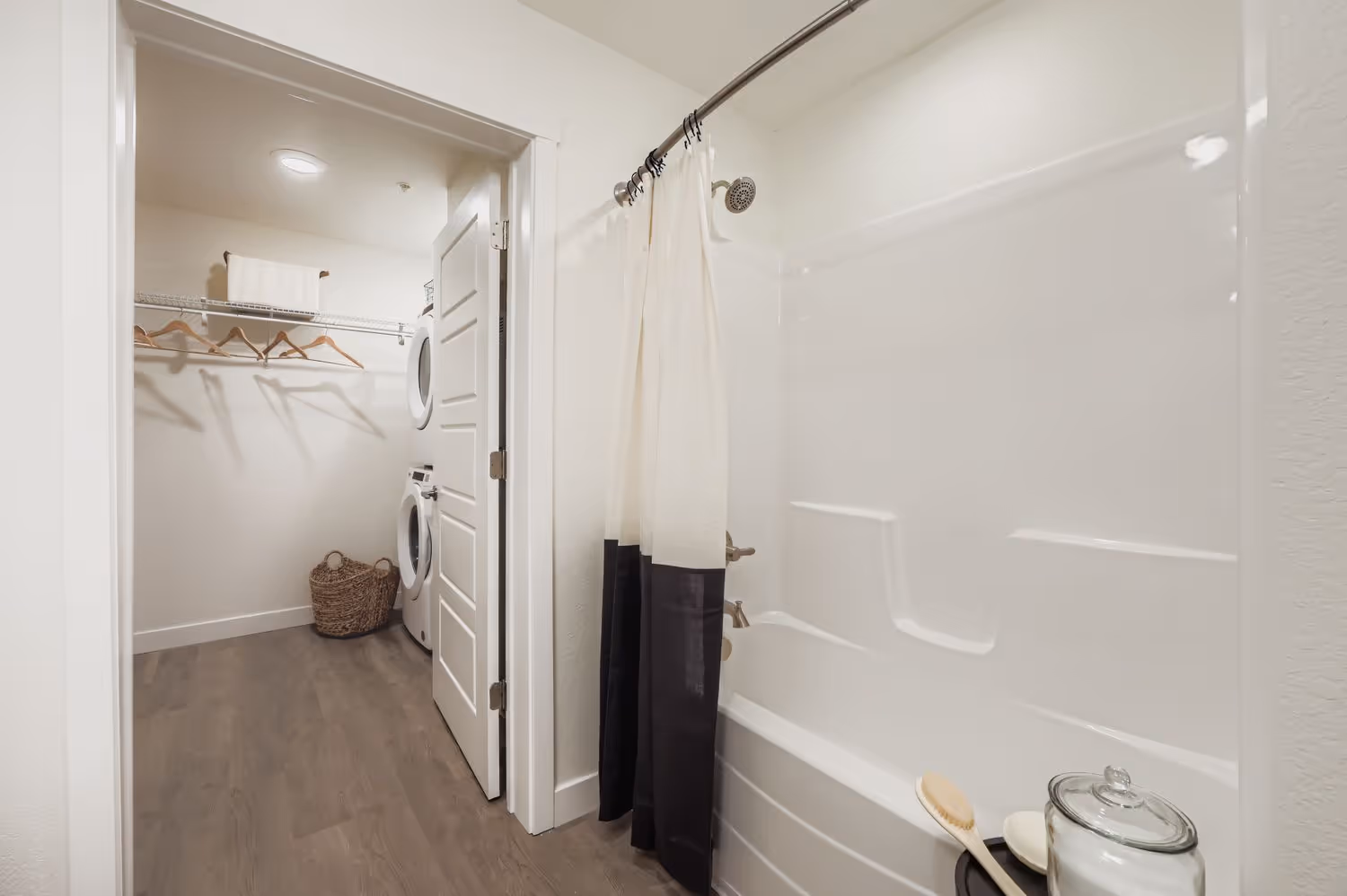 Apartment bathroom with a bathtub and a view into the adjoining walk-in closet and laundry area at Avian Apartments in Colorado Springs, CO.