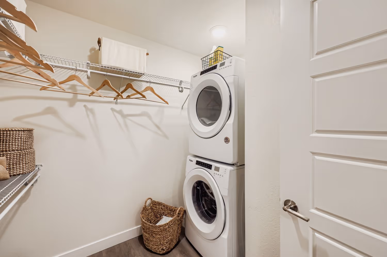 In-unit laundry closet with a stackable washer and dryer and wire shelving for storage at Avian Apartments in Colorado Springs, CO.