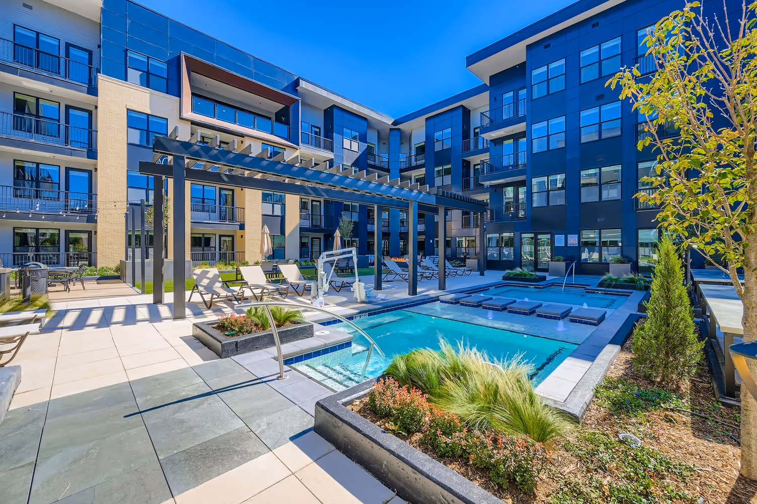 Resort-style courtyard and pool deck with integrated hot tubs, surrounded by modern apartment buildings at Avian Apartments in Colorado Springs, CO.