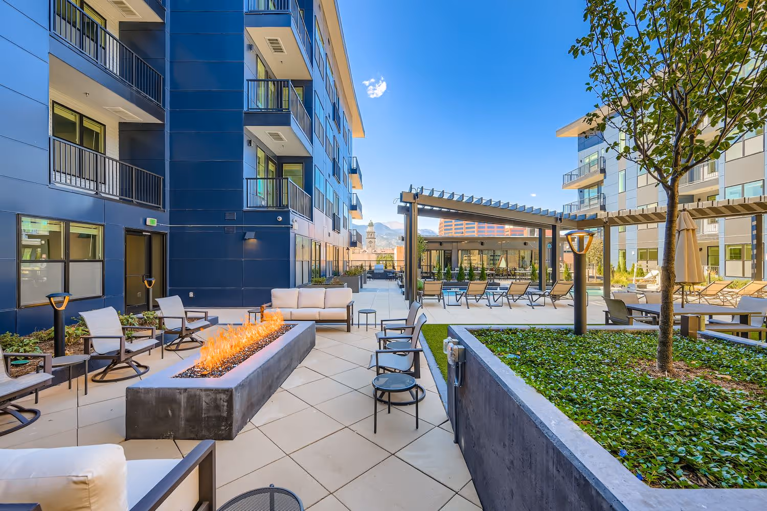 Outdoor resident fire pit lounge area and social space with modern seating, surrounded by the apartment buildings at Avian Apartments in Colorado Springs, CO.